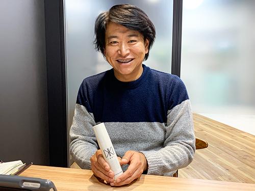 美容液「イッキ　オールインワンセラム」を手にする中沢敦社長